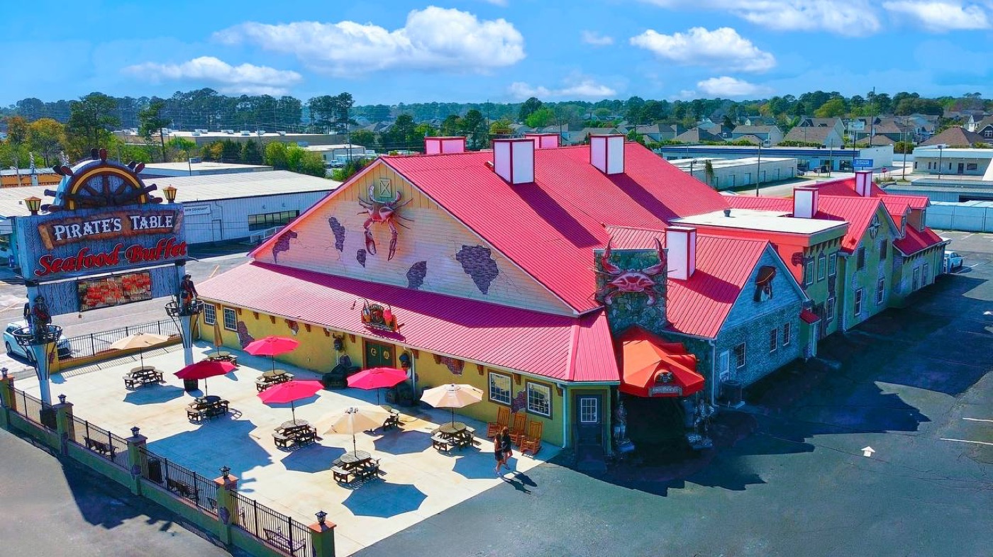 Aerial view of Pirate's Table Seafood Buffet exterior with iconic red roof, pirate signage, and outdoor patio in Surfside Beach, SC